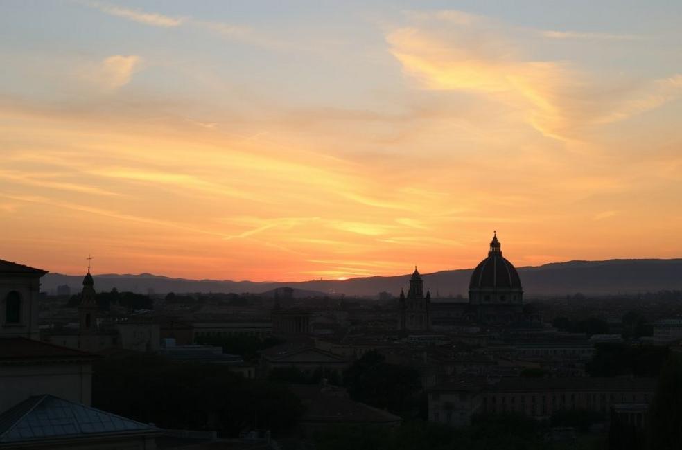 Pôr do sol em Roma com silhuetas de monumentos famosos.
