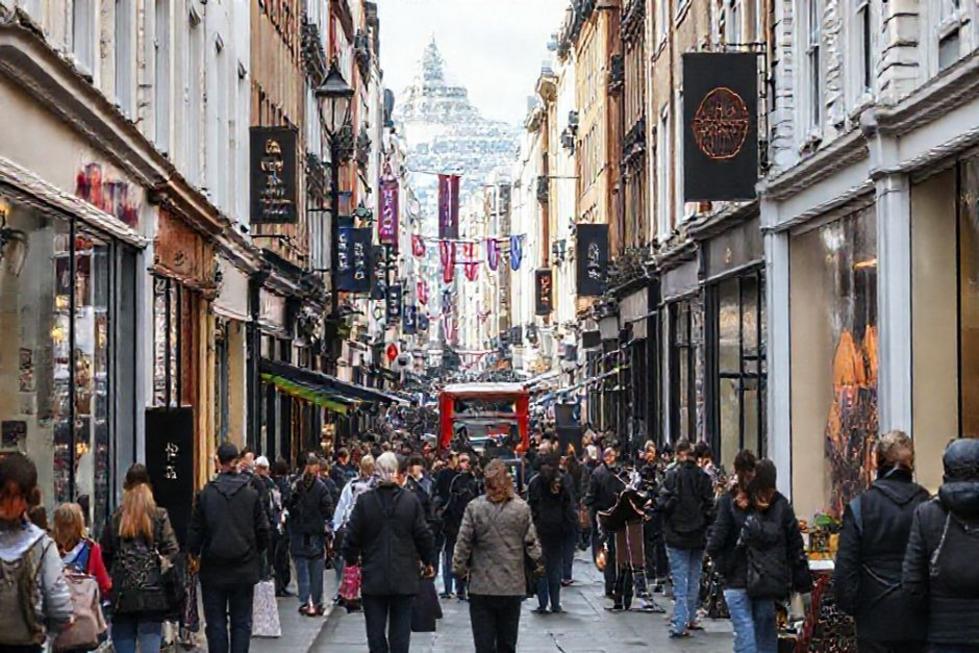 Uma rua movimentada de Londres com pessoas andando e artistas de rua.