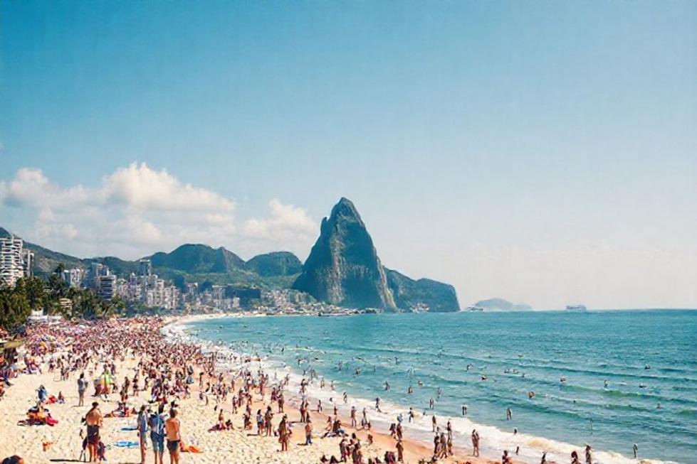 Praia do Rio de Janeiro com turistas e Pão de Açúcar ao fundo