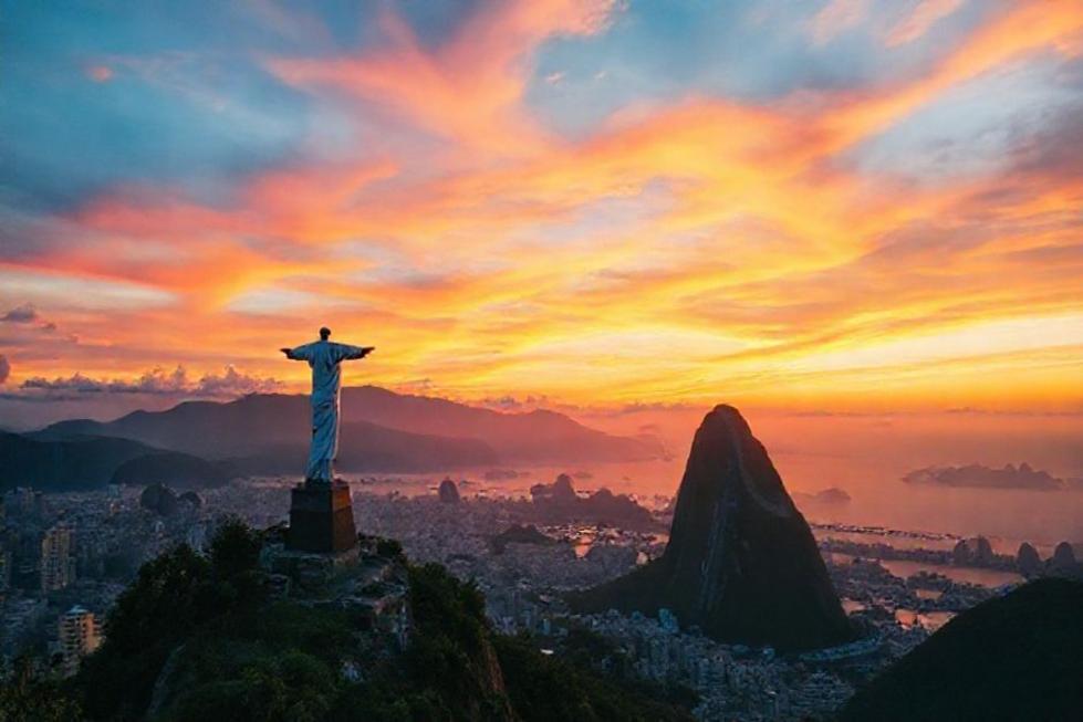 Vista do pôr do sol sobre o Rio de Janeiro com o Cristo Redentor e o Pão de Açúcar.