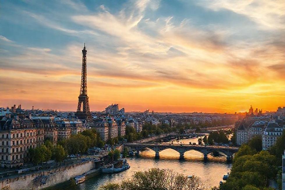 Vista panorâmica de Paris com a Torre Eiffel ao fundo durante o pôr do sol.