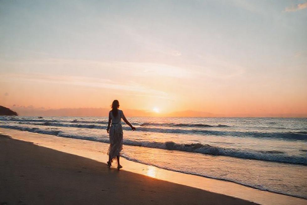 Casal caminhando na praia de Florianópolis ao pôr do sol.