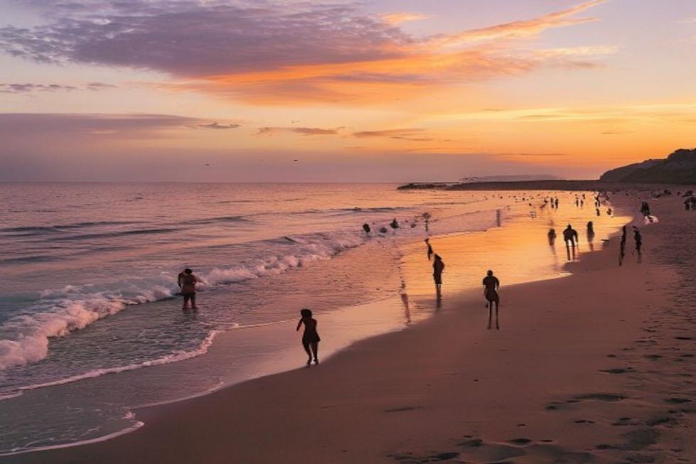 Praia de Fortaleza ao pôr do sol, com turistas relaxando.
