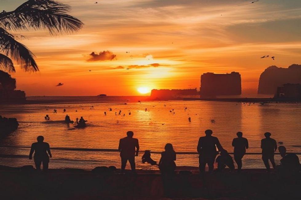 Pôr do sol sobre a costa de Recife, com pessoas desfrutando da vista incrível.
